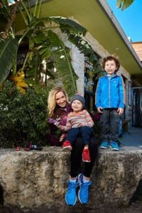 Smiling family outdoors on stone ledge