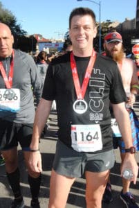 Runner smiling with medal and race bib