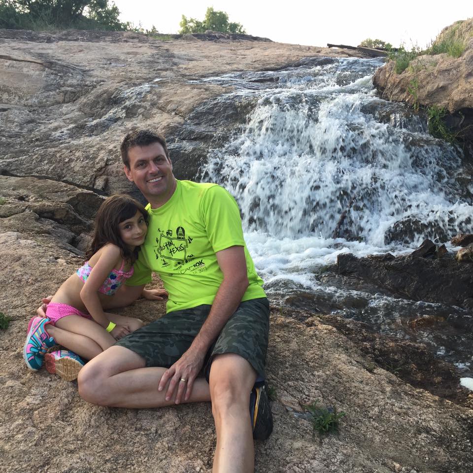 Smiling man and girl beside rocky waterfall Smiling man and girl beside rocky waterfall