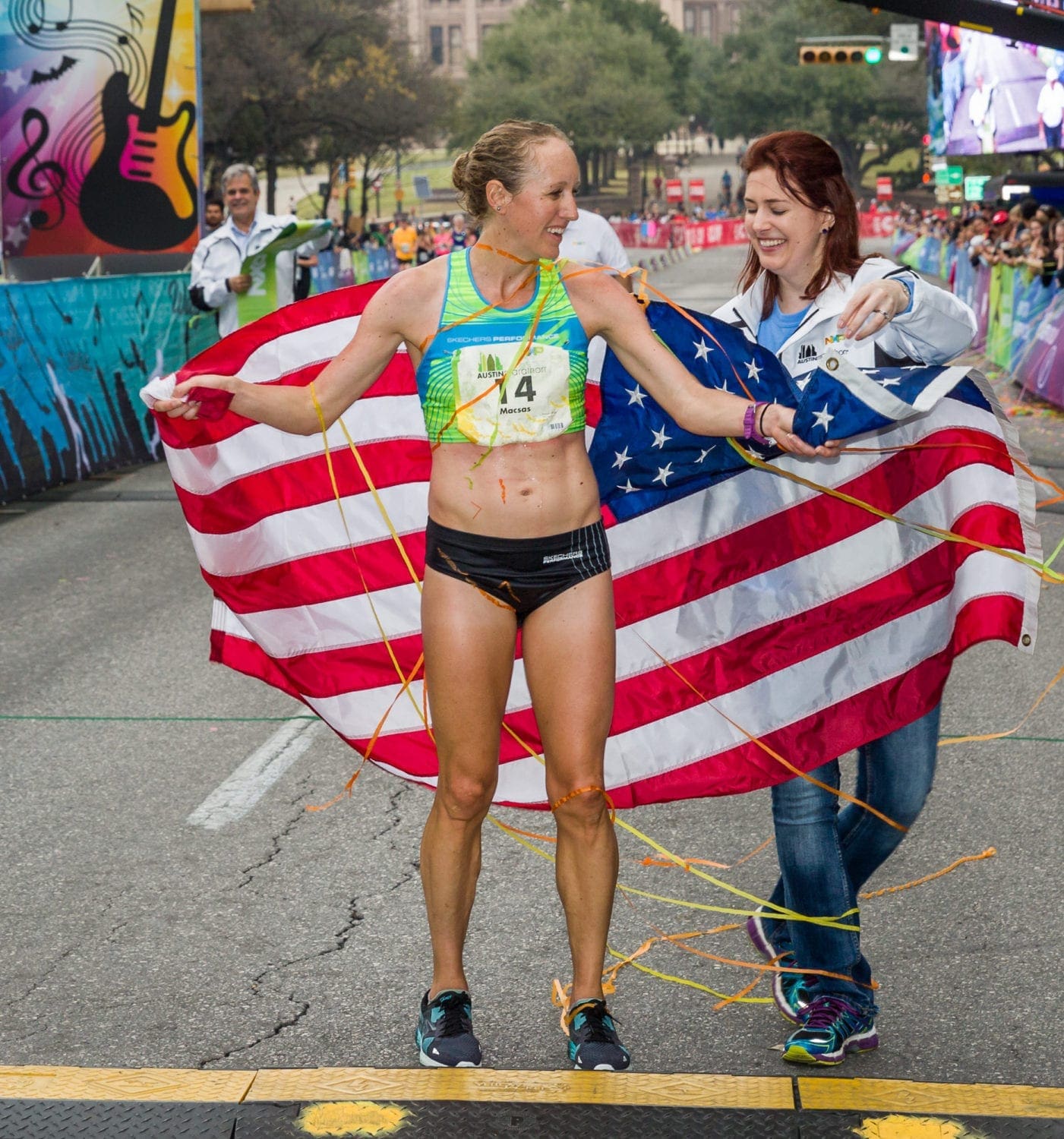 Allison Macsas draped in the American flag after winning the 2017 Austin Marathon.