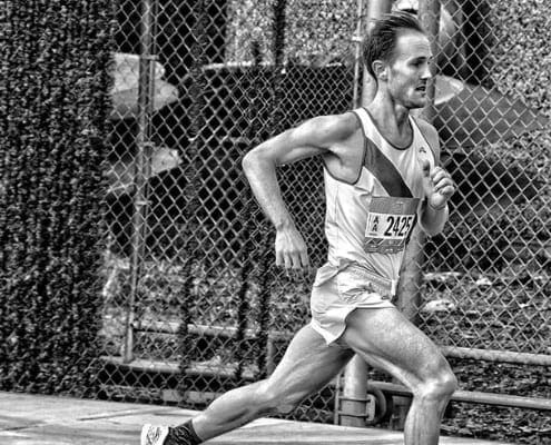 Runner sprinting along chain-link fence
