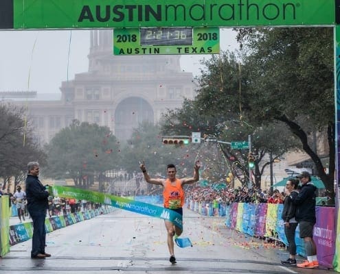 Runner crossing Austin Marathon finish line amid confetti Runner crossing Austin Marathon finish line amid confetti