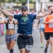 Runner excitedly crosses the 2019 Austin Half Marathon finish line. Run Austin, the #1 city in America and you will understand why people love the Austin Marathon!