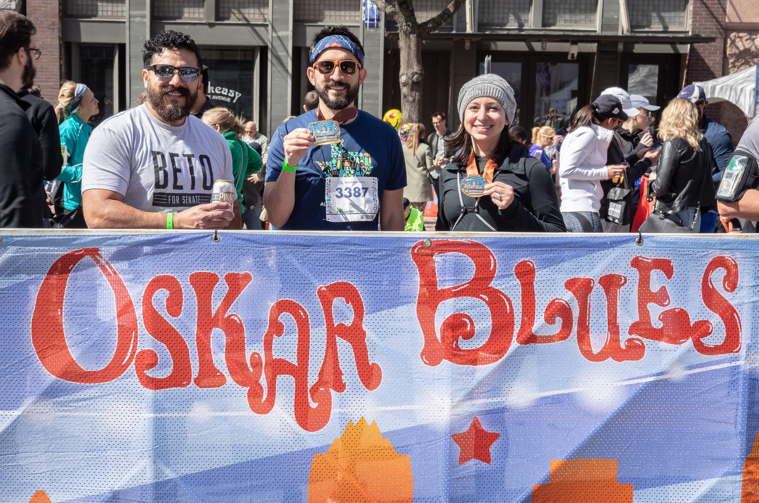 Runners show off their Austin Marathon finisher medals at the Oskar Blues Austin beer garden in the Austin Marathon's 3-block-long finish line festival.