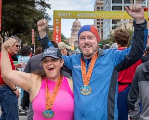 Two runners celebrate after crossing the 2019 Austin Half Marathon finish line.