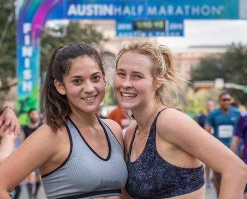 Two female runners pose after completing the 2019 Austin Half Marathon. Follow this free half marathon training plan and you'll cross the 2020 Austin Half Marathon finish line.