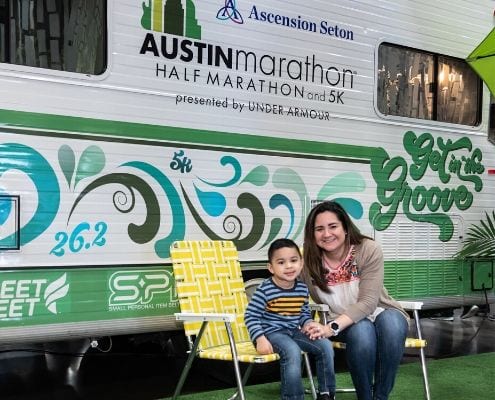 Image of mother and son in front of the Austin Marathon Winnebago at the 2019 Austin Marathon expo. Winnie is returning and will be a 2020 expo highlight.