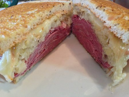 Image of a sandwich from New World Deli stacked high with meat and cheese. New World Deli is one of 5 Austin restaurants along the Austin Marathon course that people should visit.