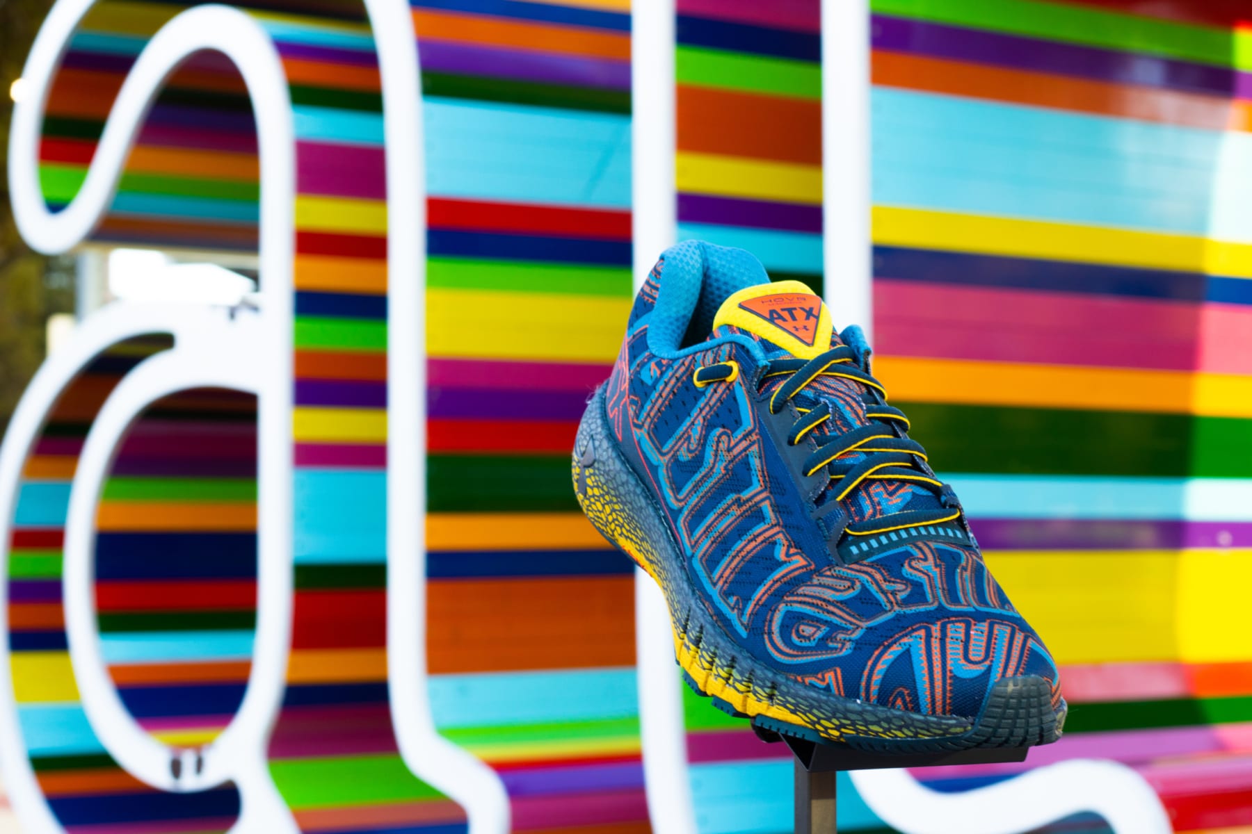 Image of the limited-edition Under Armour HOVR Machina ATX shoe in front of a multi-colored ATX sign. The Austin Marathon is giving away a pair of these shoes every day in April for their 30th Anniversary Giveaway!