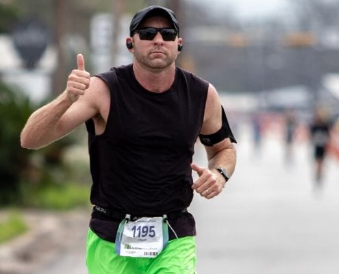 Image of runner giving the thumbs up while listening to music during the 2020 Austin Marathon. Read this blog and listen to the 10 most recent March running playlist additions.