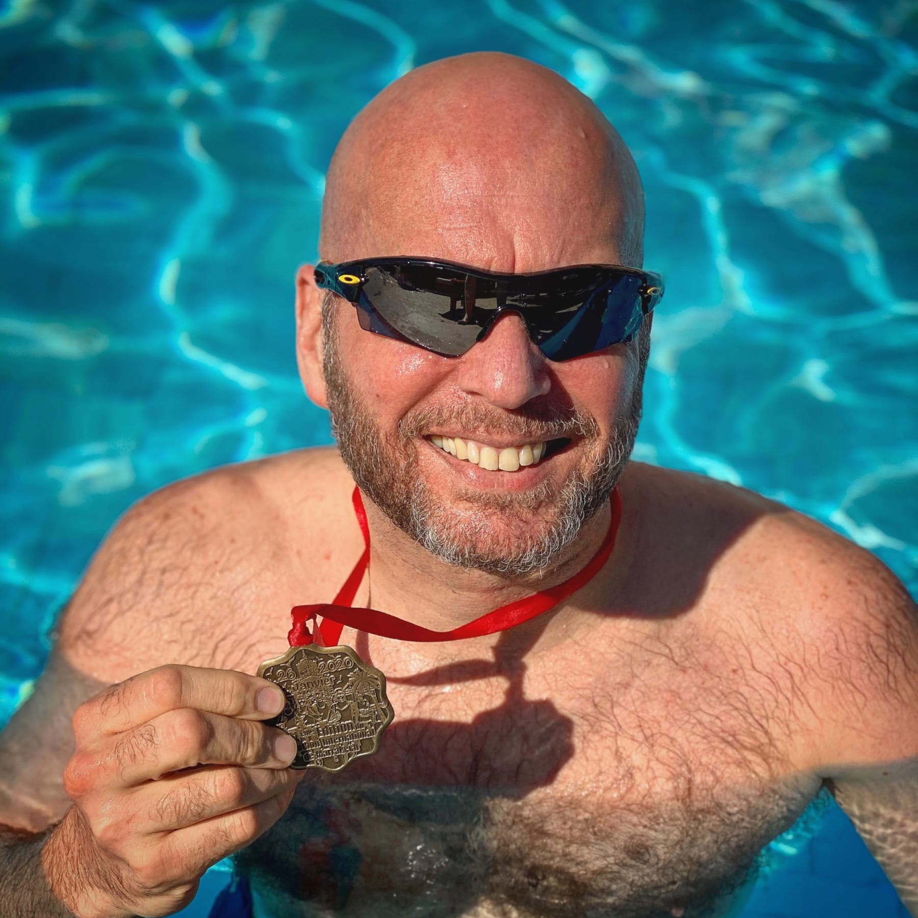 Image of Jonathan Acott in a pool showing off his medal from the Marrakesh Marathon. Read about his journey to run the world and how the Austin Marathon is next!