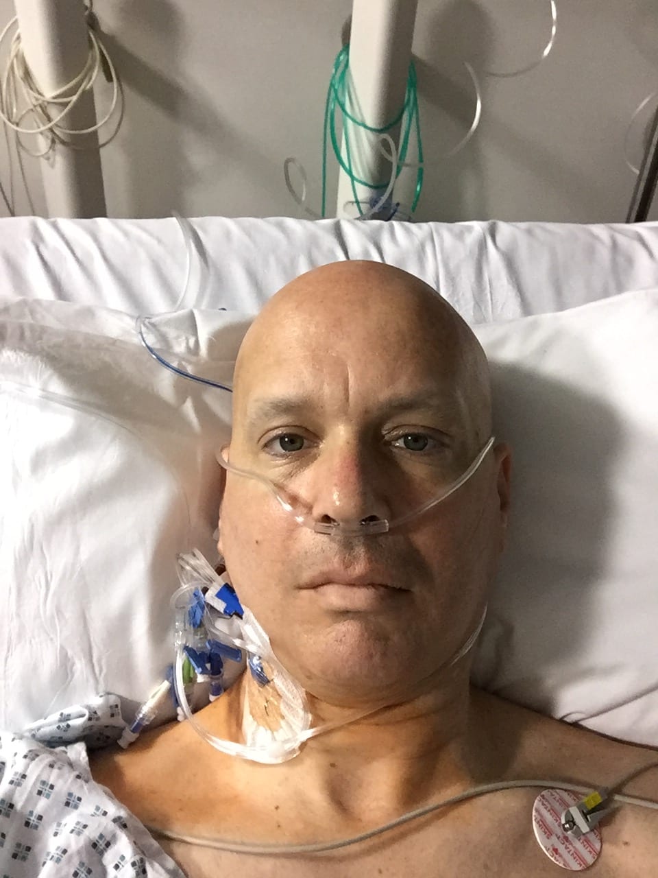 Image of Jonathan Acott in a hospital bed fighting one of his six diagnosed cancers. Read about his journey to run the world and how the Austin Marathon is next!