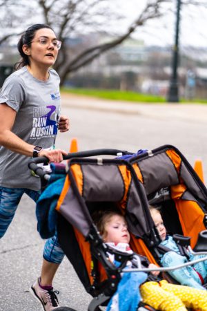 Image of a mother pushing a double-stroller during the 2020 Austin Marathon KXAN SimpleHealth 5K. Thank mom with the downloadable Mother's Day coupon book in this blog!