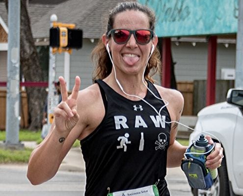 Image of runner giving the peace sign while listening to music during the 2020 Austin Marathon. Read this blog and listen to the 10 recent April running playlist additions.