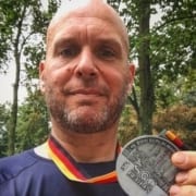 Image of Jonathan Acott showing off his medal from the Berlin Marathon. Read about his journey to run the world and how the Austin Marathon is next!