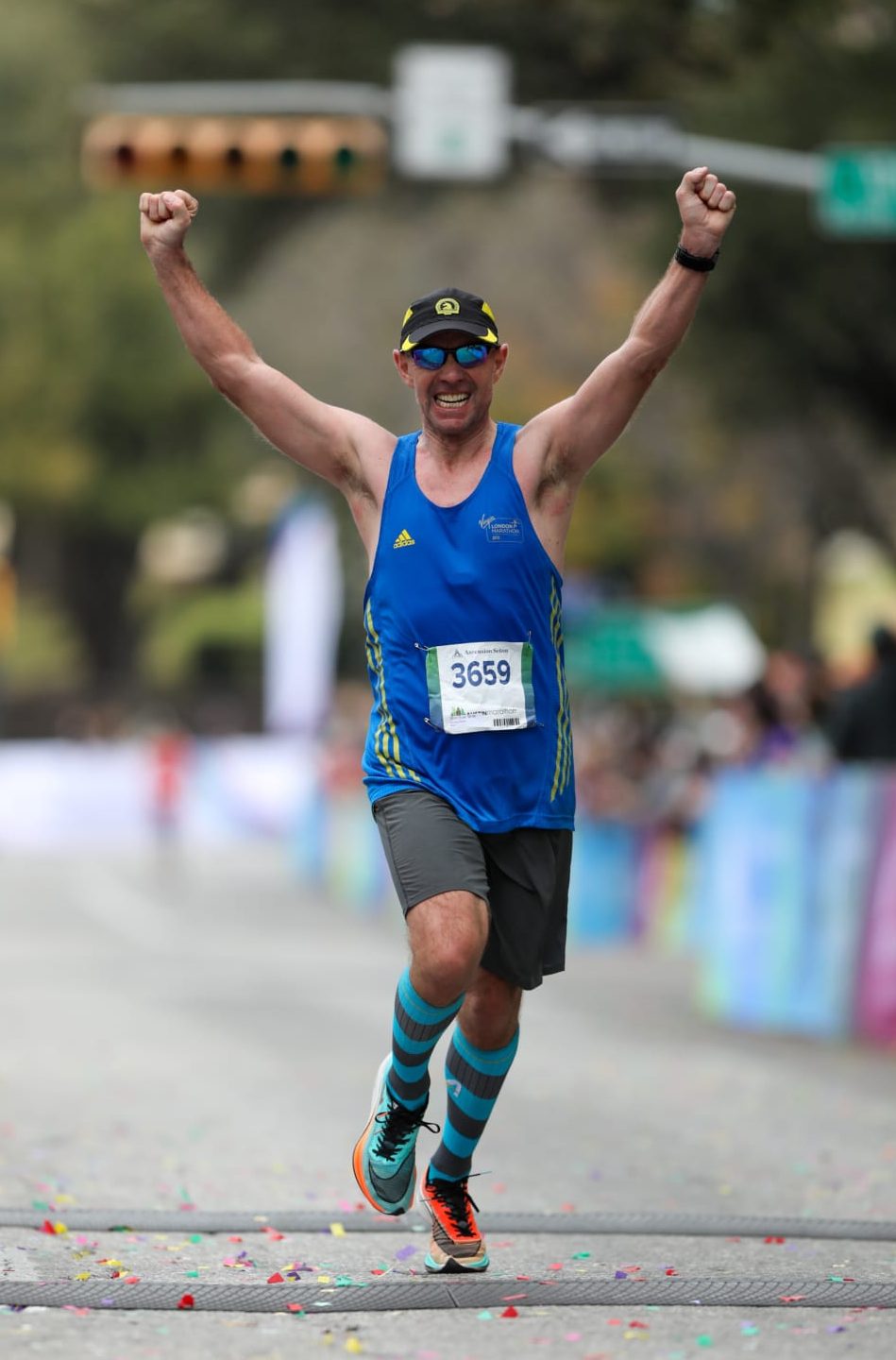 Image of a male runner with his arms raised in triumph crossing the 2020 Ascension Seton Austin Marathon finish line. Credit to Scott Flathouse.