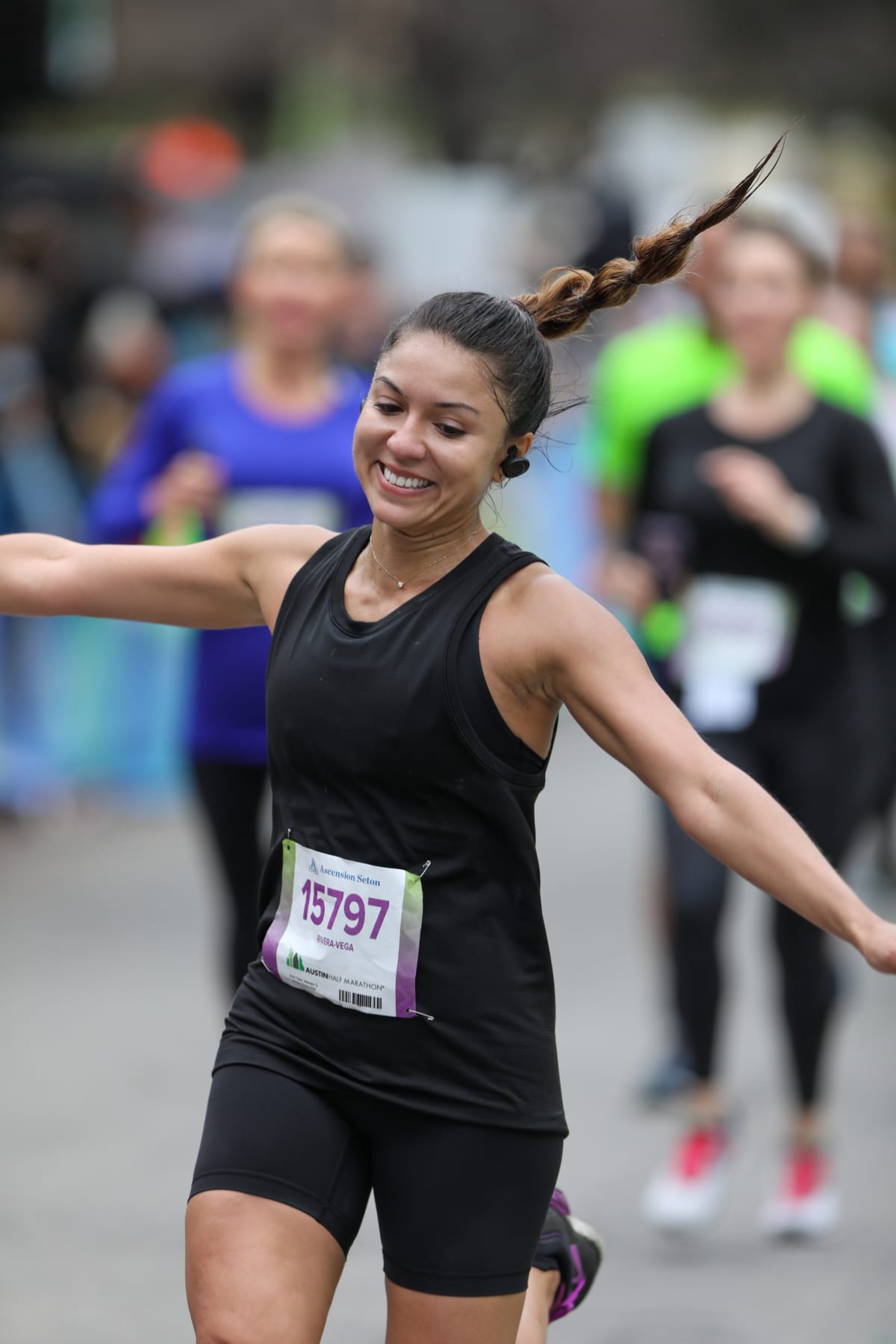 Image of female runner smiling with her arms outstretched, crossing the 2020 Austin Half Marathon finish line. Read the advice in this blog and learn how to increase your mileage.