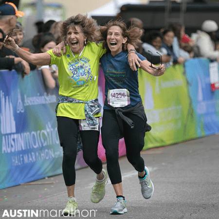 Two women embrace as they finish half marathonn in Austin Texas