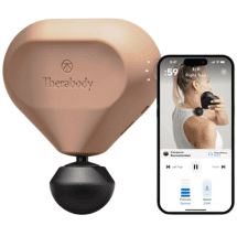 A beige Therabody massage device with a black spherical attachment is shown next to a smartphone that displays a workout app. The app screen features a woman using the device on her shoulder. It's an ideal running gift for post-marathon recovery, perfect for events like the Austin Marathon or as a Father’s Day treat. Austin Marathon Half Marathon & 5K