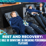 Three individuals are relaxing on reclining chairs covered with blue blankets. Two are lying back asleep, and one is sitting upright, looking ahead. The text reads "Rest and Recovery: The Role of Downtime in Breaking Runners' Performance Plateaus." The border is decorated with blue and purple patterns. Austin Marathon Half Marathon & 5K