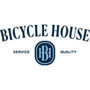 The image showcases the logo for "Bicycle House." It features the name "Bicycle House" in bold, arched text above a circular emblem with the initials "BH." The words "Service" and "Quality," inspired by their Texas Marathon sponsorship, are positioned on either side of the emblem. The logo is primarily in blue tones. Austin Marathon Half Marathon & 5K