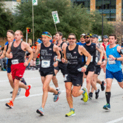 A group of people running in a race, each focused on maintaining their ideal marathon pace. Austin Marathon Half Marathon & 5K