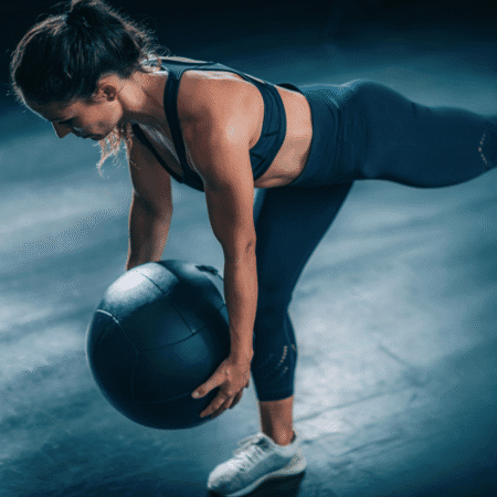 A woman holding a ball, demonstrating strength training for runners—a key part of runner workouts that builds power without bulking. Austin Marathon Half Marathon & 5K