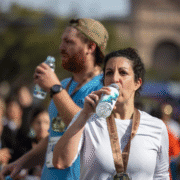 Two marathon runners with finisher medals drink water after a race, showing the exhaustion and relief typical of race day. Their dedication raises questions about what runners eat and how a runner's diet impacts performance and recovery. Austin Marathon Half Marathon & 5K