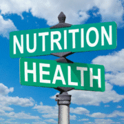 Two green street signs with white text reading "NUTRITION" and "HEALTH" intersect against a bright blue sky—a perfect snapshot for runners seeking guidance on what to eat and how to navigate nutrition myths. Austin Marathon Half Marathon & 5K