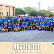 A large group of people in matching blue shirts pose together in a parking lot for a group photo. The text below reads, "Austin Fit Free Group Run," with a beige map-themed banner highlighting the Austin community spirit. Austin Marathon Half Marathon & 5K