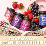 A mesh bag filled with jars of Good Good jams, fresh strawberries, and grapes sits on a pink background. Text below reads: "GIVEAWAY: Your chance to win jams in 1 of 2 GOOD GOOD Goodie packs!. Austin Marathon Half Marathon & 5K