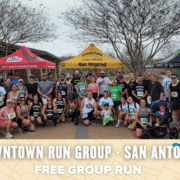 A large group of runners pose together outdoors under tents at a park for a Downtown Run Group event in San Antonio. The text reads “Downtown Run Group · San Antonio. Free group run open to all.”. Austin Marathon Half Marathon & 5K