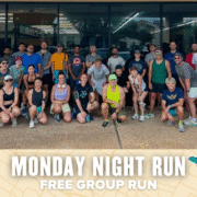A large group of runners in athletic wear pose and smile together outside a building. Text below reads, "Monday Night Run — Free Group Run" against a decorative background, inviting all to join this welcoming community event. Austin Marathon Half Marathon & 5K