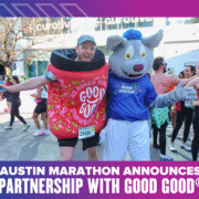 Two people at the Austin Marathon: one is dressed as a jar of GOOD GOOD strawberry jam, the other as a wolf mascot in an “Austin Marathon” shirt. Both are smiling with arms outstretched, celebrating the Ascension Seton partnership announcement. Austin Marathon Half Marathon & 5K
