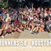 A large, cheerful group of Houston runners poses together outdoors, many wearing medals and colorful athletic gear. A banner below reads: "RUNNERS 58 - HOUSTON FREE GROUP RUN. Austin Marathon Half Marathon & 5K