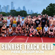 A large group of smiling runners poses together on a track, with a city skyline and trees in the background. Text below reads, "Sunrise Track Club Free Group Run," highlighting this energizing group run event with music and running graphics. Austin Marathon Half Marathon & 5K