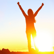 A person stands outdoors at sunrise or sunset with arms raised in triumph, silhouetted against the bright sun—a powerful image of staying motivated and overcoming mental hurdles. Austin Marathon Half Marathon & 5K