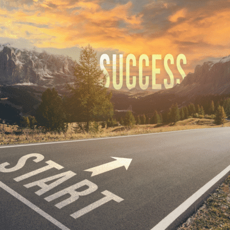 A paved road with "START" and an arrow painted on it leads toward mountains at sunset. "SUCCESS" appears in large letters in the sky ahead, inspiring the runner’s mental reset and symbolizing a journey fueled by setting mini goals. Austin Marathon Half Marathon & 5K