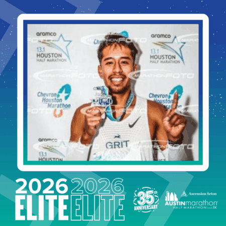 A smiling male runner from the Elite Group holds up a finisher medal after a race, wearing a white 