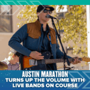 A musician wearing sunglasses, a cap, and a jacket plays an electric guitar and sings into a microphone on an outdoor stage. Text below reads: “Austin Marathon turns up the volume with live bands along the marathon course.”. Austin Marathon Half Marathon & 5K