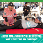 A smiling man in running gear lies on a red massage table as another man massages his leg at the Austin Marathon Finish Line Festival, celebrating amid the lively crowd and festive tents in the background. Austin Marathon Half Marathon & 5K