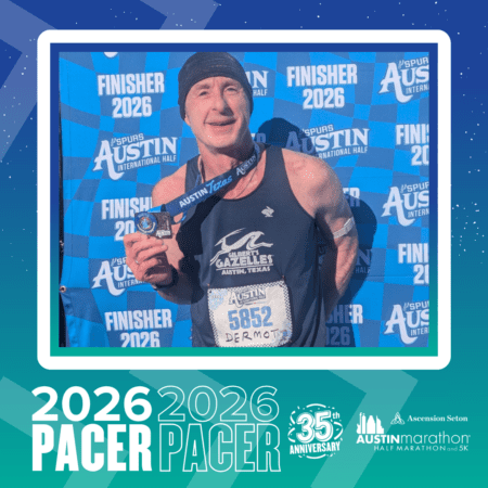 A smiling man wearing a running tank top and cap holds a race medal and bib number 5852. He stands in front of a 
