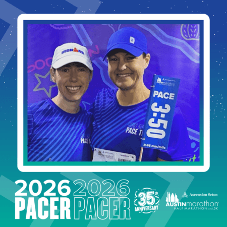 Two smiling Pacer Group marathon pacers in blue running shirts and hats pose together, holding a 