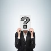 A person in a black suit holds a white sign with a large black question mark in front of their face, symbolizing the uncertainty often felt during post marathon physical and mental recovery, against a plain light background. Austin Marathon Half Marathon & 5K