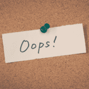 A corkboard with a white note pinned by a green pushpin. The note has "Oops!" written in large, casual black letters—a lighthearted reminder that even marathon training or base building can have its unexpected moments. Austin Marathon Half Marathon & 5K