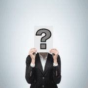 A person in a black suit holds up a paper with a large black question mark in front of their face, obscuring their identity, as if questioning their marathon training or running preparation, against a plain light background. Austin Marathon Half Marathon & 5K