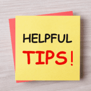 A yellow sticky note with "HELPFUL TIPS!" in bold black and red letters sits atop a red sticky note on a light wood surface—perfect for jotting down marathon training or running preparation reminders. Austin Marathon Half Marathon & 5K