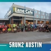 A large group of runners from the Buda Running Club pose together outside Lane Cafe at dawn or dusk, with "5RUN2 Austin" in bold white letters at the bottom. The scene features a blue and teal border with arrow graphics. Austin Marathon Half Marathon & 5K