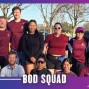 A group of ten people, some in maroon shirts and others in athletic wear, pose and smile outdoors on a sunny day with trees in the background. The text "BOD SQUAD" at the bottom highlights this spirited Buda Running Club group run. Austin Marathon Half Marathon & 5K