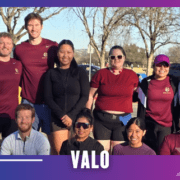 A group of eleven people, some standing and some kneeling, pose outside in athletic wear after a Group Run. The scene is sunny with trees in the background, and the word "VALO" is displayed at the bottom. Austin Marathon Half Marathon & 5K